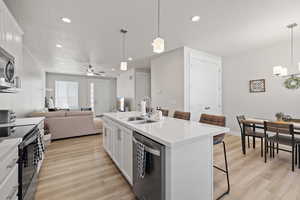 Kitchen with a kitchen bar, a sink, stainless steel appliances, and light wood-type flooring