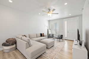 Living area featuring light wood-style flooring, ceiling fan, recessed lighting, and a textured ceiling
