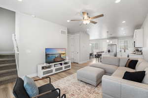 Living room featuring stairway, a ceiling fan, light wood-type flooring, visible vents, and recessed lighting