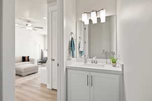 Bathroom with a textured ceiling, ceiling fan, wood finished floors, vanity, and ensuite bath