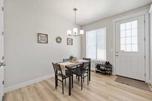 Dining room featuring baseboards, light wood-type flooring, and an inviting chandelier