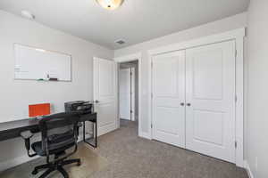 Office space featuring baseboards, visible vents, carpet flooring, and a textured ceiling