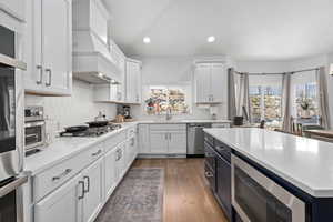 Kitchen featuring white cabinets, a sink, stainless steel appliances, and custom exhaust hood
