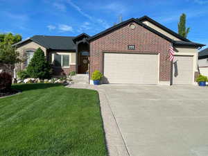 Ranch-style house with brick siding, a garage, a front yard, and concrete driveway