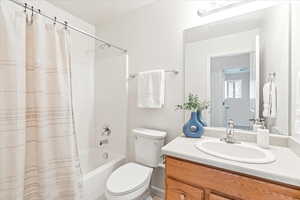 Bathroom with toilet, vanity, and shower / bath combination with curtain
