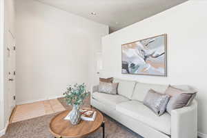 Living area with carpet floors, tile patterned floors, and baseboards