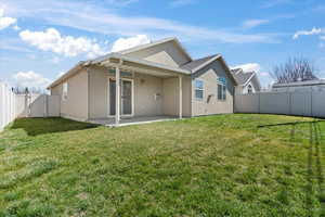 Rear view of house with a fenced backyard, a gate, a lawn, a patio, and stucco siding