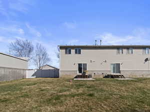 Rear view of property featuring entry steps, fence, and a yard