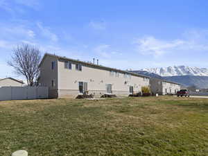 Back of property featuring a lawn, entry steps, fence, and a mountain view