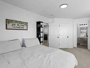 Carpeted bedroom featuring baseboards, ensuite bath, and a sink