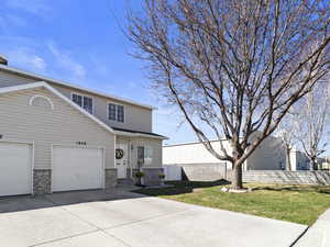 View of front facade with fence, an attached garage, a front yard, brick siding, and driveway