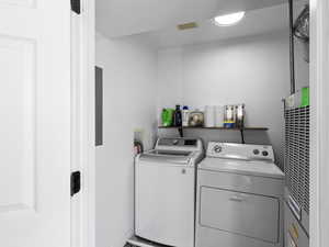 Laundry area with visible vents, electric panel, and washer and dryer