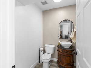 Bathroom featuring visible vents, baseboards, toilet, wood finished floors, and vanity