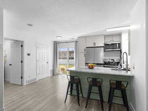 Kitchen featuring a sink, a kitchen bar, appliances with stainless steel finishes, and a peninsula