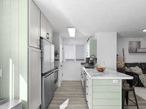Kitchen featuring a sink, light wood finished floors, a breakfast bar area, appliances with stainless steel finishes, and open floor plan