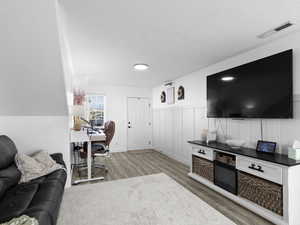 Office space featuring wainscoting, wood finished floors, a textured ceiling, and visible vents