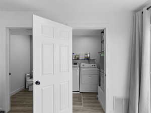 Clothes washing area featuring visible vents, independent washer and dryer, baseboards, wood finished floors, and laundry area