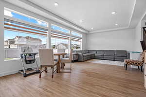 Living room featuring recessed lighting, a residential view, baseboards, a raised ceiling, and light wood-style flooring