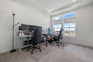 Carpeted office space featuring a tray ceiling, baseboards, and recessed lighting