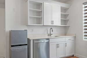 Bar with baseboards, a sink, and appliances with stainless steel finishes