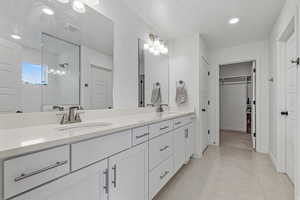 Full bathroom featuring double vanity, a sink, tile patterned floors, and a tile shower