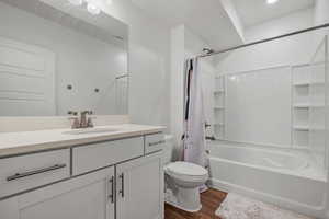 Bathroom with vanity, toilet, visible vents, shower / bath combination with curtain, and wood finished floors