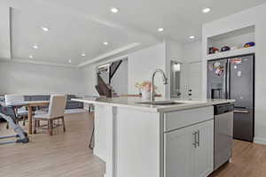 Kitchen with light countertops, a sink, an island with sink, light wood-style flooring, and appliances with stainless steel finishes