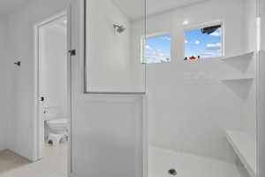 Full bath with toilet, tile patterned flooring, and a tile shower