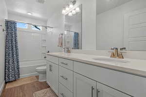 Full bath with double vanity, wood finished floors, toilet, and a sink