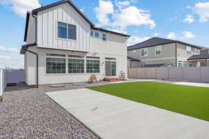 Rear view of property with stucco siding, a fenced backyard, board and batten siding, entry steps, and a lawn