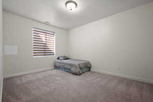 Carpeted bedroom with baseboards, a textured ceiling, and visible vents