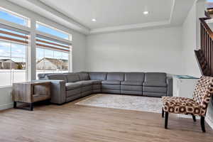 Living area with wood finished floors, recessed lighting, and a raised ceiling