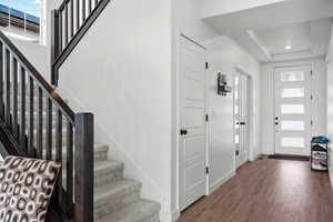 Foyer with baseboards, stairway, and wood finished floors