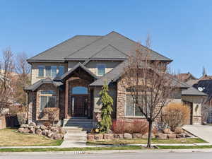 Craftsman house with stone siding, fence, a front lawn, driveway, and a shingled roof