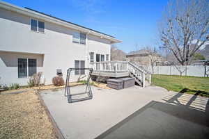 Rear view of house featuring a patio area, stucco siding, a deck, fence, and a lawn