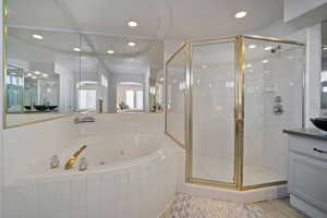 Bathroom featuring a jetted tub, a stall shower, recessed lighting, and vanity