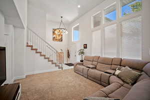 Carpeted living room featuring stairs, a notable chandelier, a high ceilings and recessed lighting