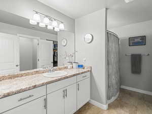 Full bathroom featuring curtained shower, vanity, tile patterned flooring, baseboards, and visible vents