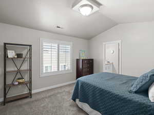 Carpeted bedroom featuring connected bathroom, baseboards, lofted ceiling, and visible vents