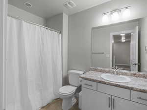 Full bathroom featuring visible vents, toilet, vanity, a shower with curtain, and tile patterned flooring