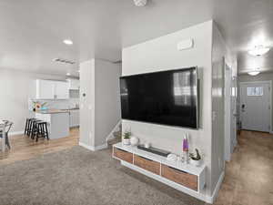 Living area with visible vents, light wood finished floors, baseboards, stairway, and light colored carpet