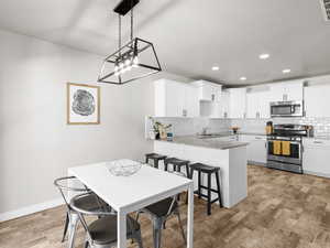 Kitchen featuring backsplash, a kitchen bar, a peninsula, light wood-style flooring, and stainless steel appliances
