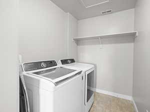 Clothes washing area featuring baseboards, visible vents, laundry area, and separate washer and dryer