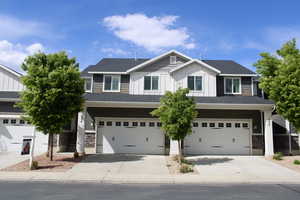 Craftsman-style house featuring board and batten siding, an attached garage, driveway, and stone siding