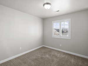 Carpeted spare room featuring baseboards and visible vents