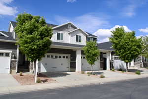Craftsman-style house with board and batten siding, concrete driveway, stone siding, and a garage