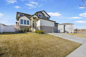 View of front of house featuring a gate, stone siding, fence, a front lawn, and a garage