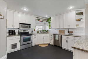 Kitchen with a sink, white cabinets, appliances with stainless steel finishes, and open shelves