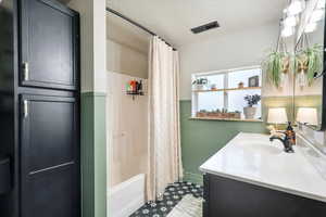 Full bath with vanity, a textured ceiling, shower / bathtub combination with curtain, and visible vents