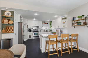 Kitchen featuring white cabinets, a peninsula, appliances with stainless steel finishes, and open shelves